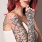 Beautiful woman with tattoos on body against light background, closeup